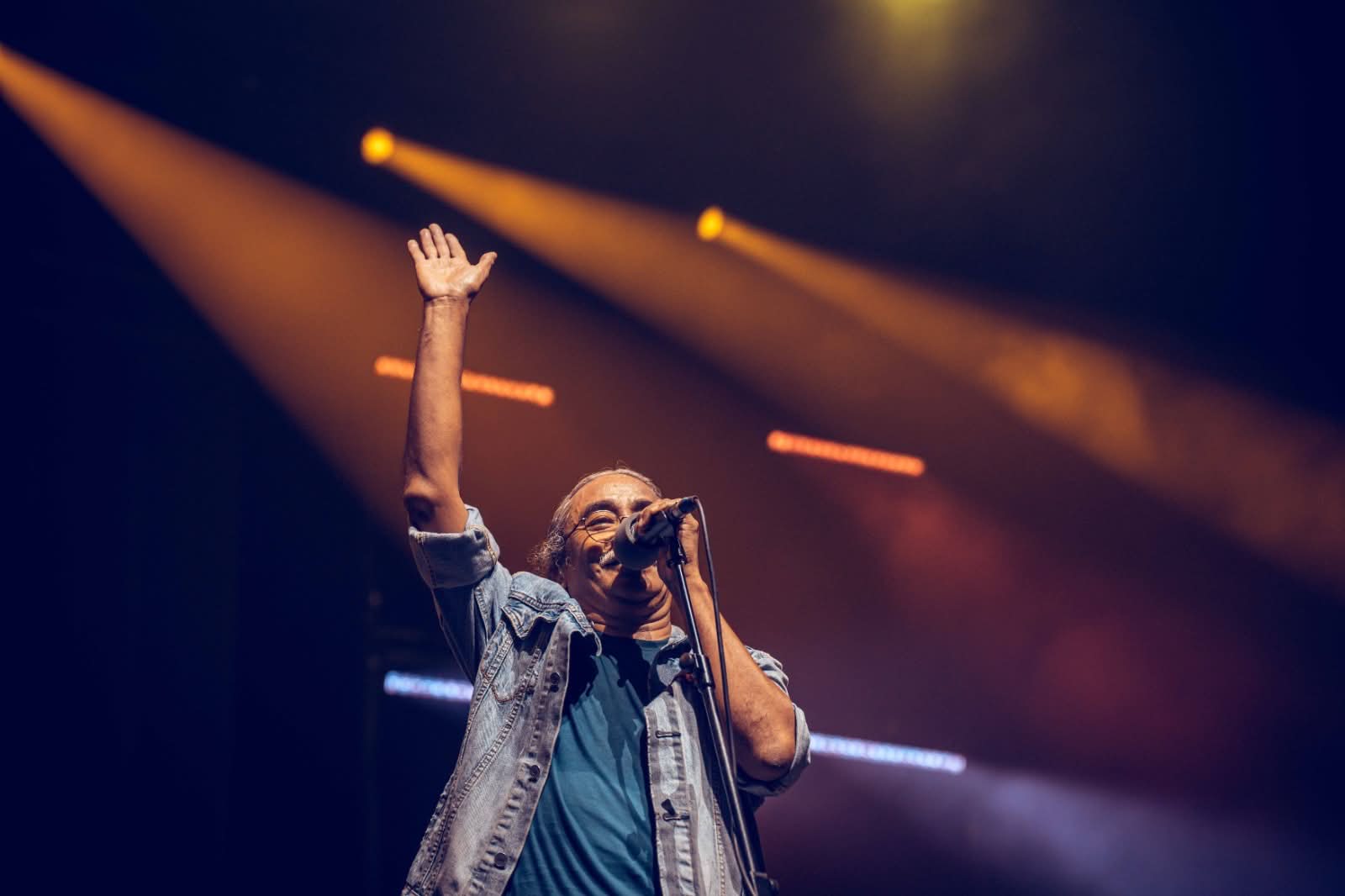 Nepathya vocalist raising a hand under golden stage lights